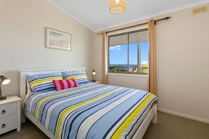 A bedroom with a bed, bedside tables, a lamp, a window with curtains, and a ceiling light. - Surf Reef (Marengo)
