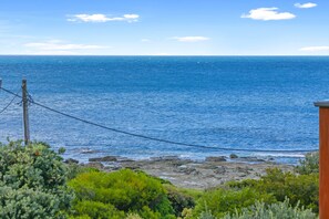 A coastal landscape with a view of the ocean, rocky shoreline, and vegetation. - Surf Reef (Marengo)
