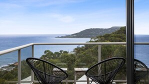 A balcony with two chairs overlooking a coastal view.