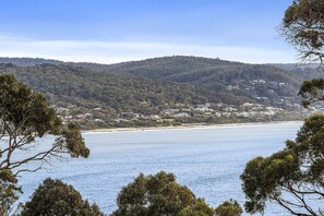 A coastal landscape with a beach, hills, and a cluster of buildings. - Apartment 26 Kalimna (Lorne)