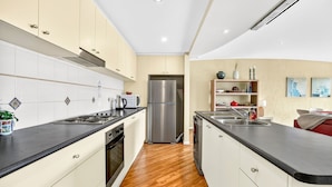 A modern kitchen with a central island, stainless steel appliances, and a wooden floor.