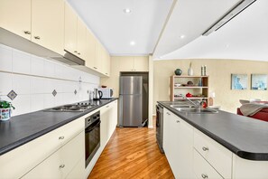 A modern kitchen with a central island, stainless steel appliances, and a wooden floor.