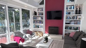 Ein modernes Wohnzimmer mit Kamin, großem Fernseher und einer Bücherwand mit Büchern und Dekoration.