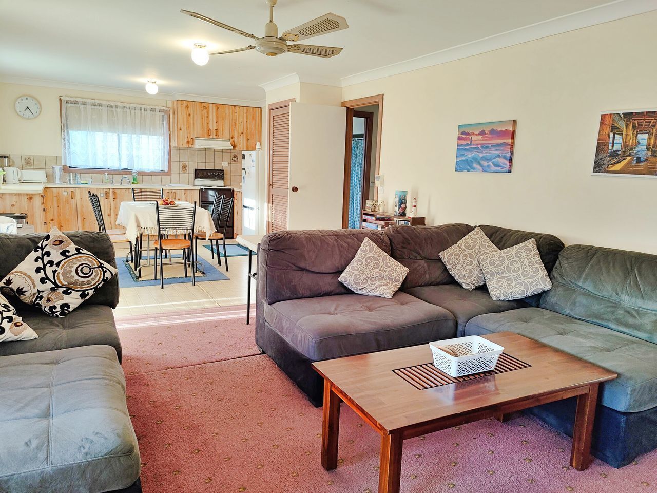 A living room with a sofa, a coffee table, and a dining area with chairs and a table.