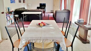 Un coin repas avec une table dressée pour quatre personnes, un canapé, un téléviseur et une bibliothèque.