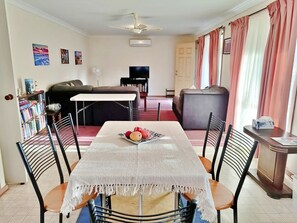 A dining area with a table set for four, a sofa, a television, and a bookshelf.