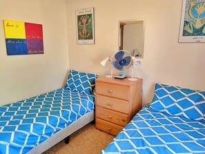 Un dormitorio con dos camas, un aparador de madera, un espejo y decoración en las paredes.