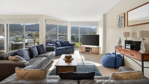 Amplia sala de estar con televisor grande, asientos cómodos y vistas al exterior.