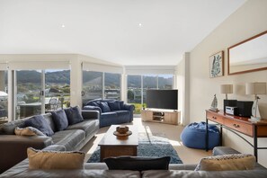 A spacious living room with a large TV, comfortable seating, and a view of the outdoors.