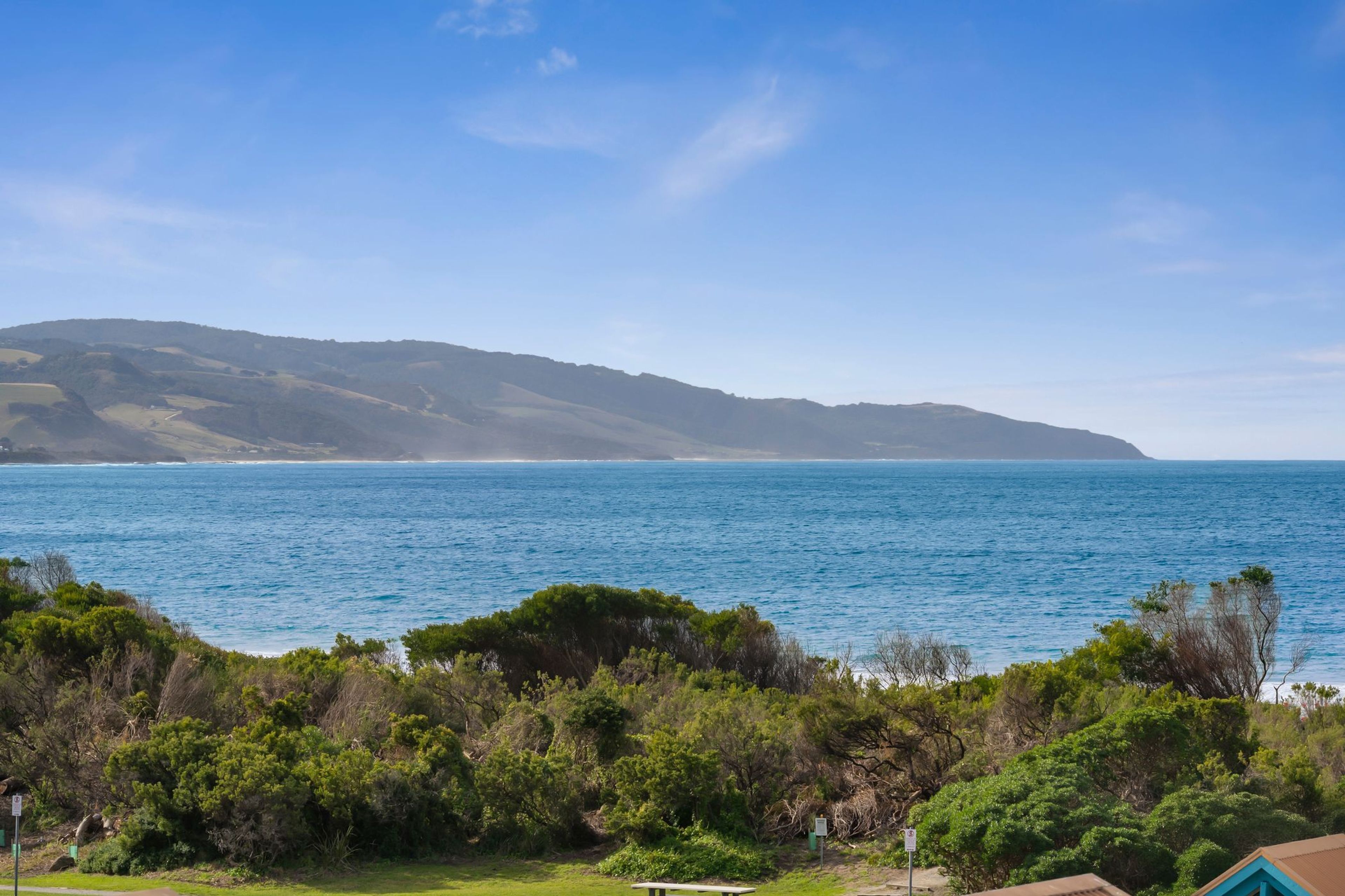 Eine Küstenlandschaft mit Blick auf das Meer und die fernen Hügel.