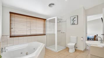 Une salle de bain moderne équipée d’une baignoire, de toilettes, d’une douche et d’un lavabo.