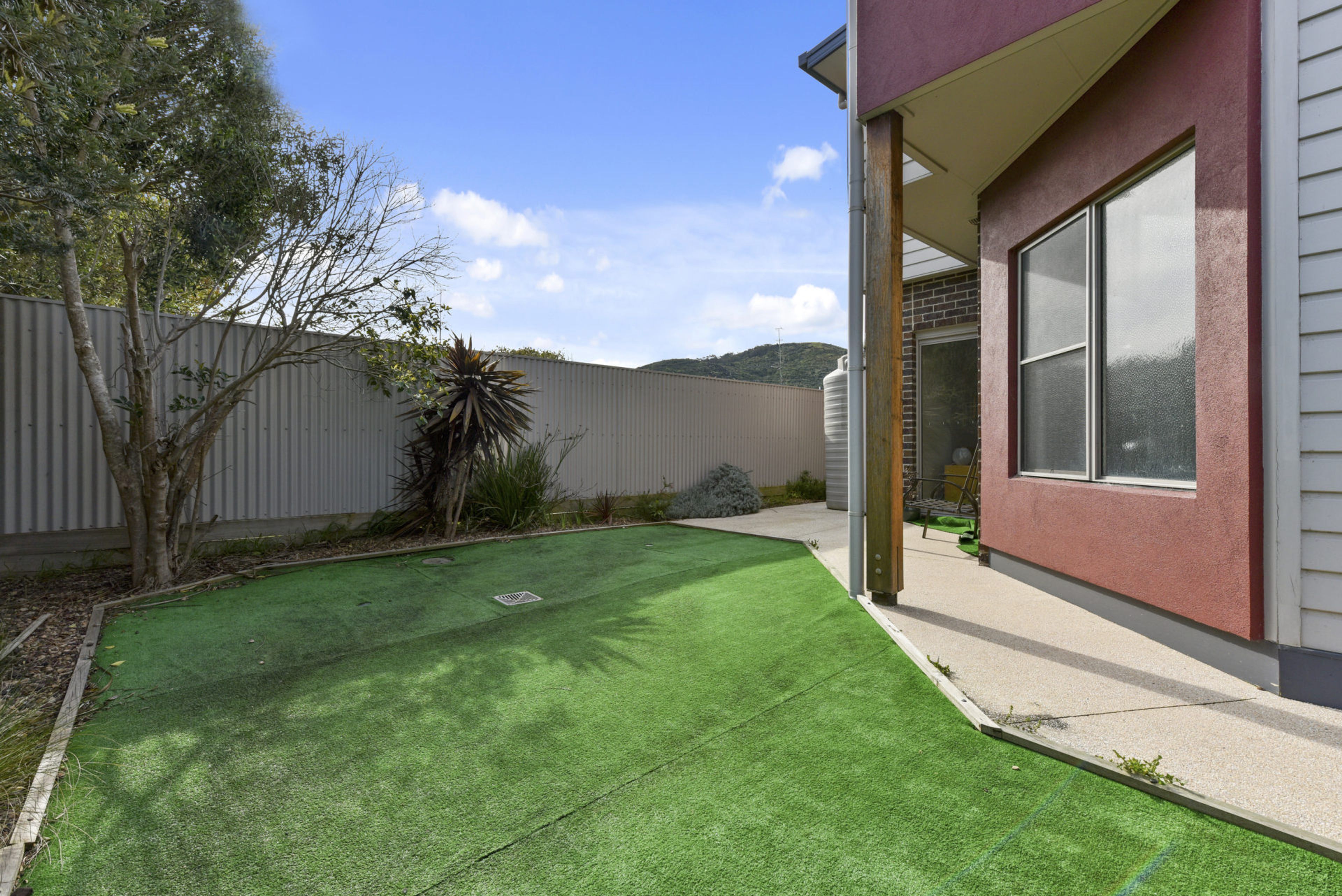 A residential property with a well-maintained lawn, a wooden deck, and a large window.