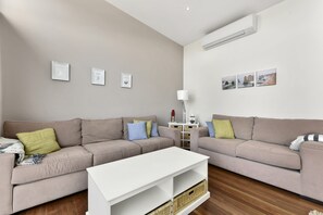 A living room with two sofas, a white coffee table, and wall-mounted pictures.