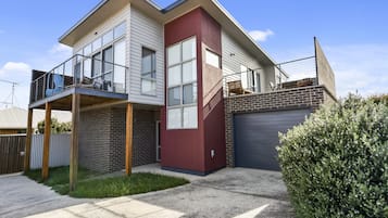 Une maison à deux étages avec un balcon, un garage et une pelouse bien entretenue.