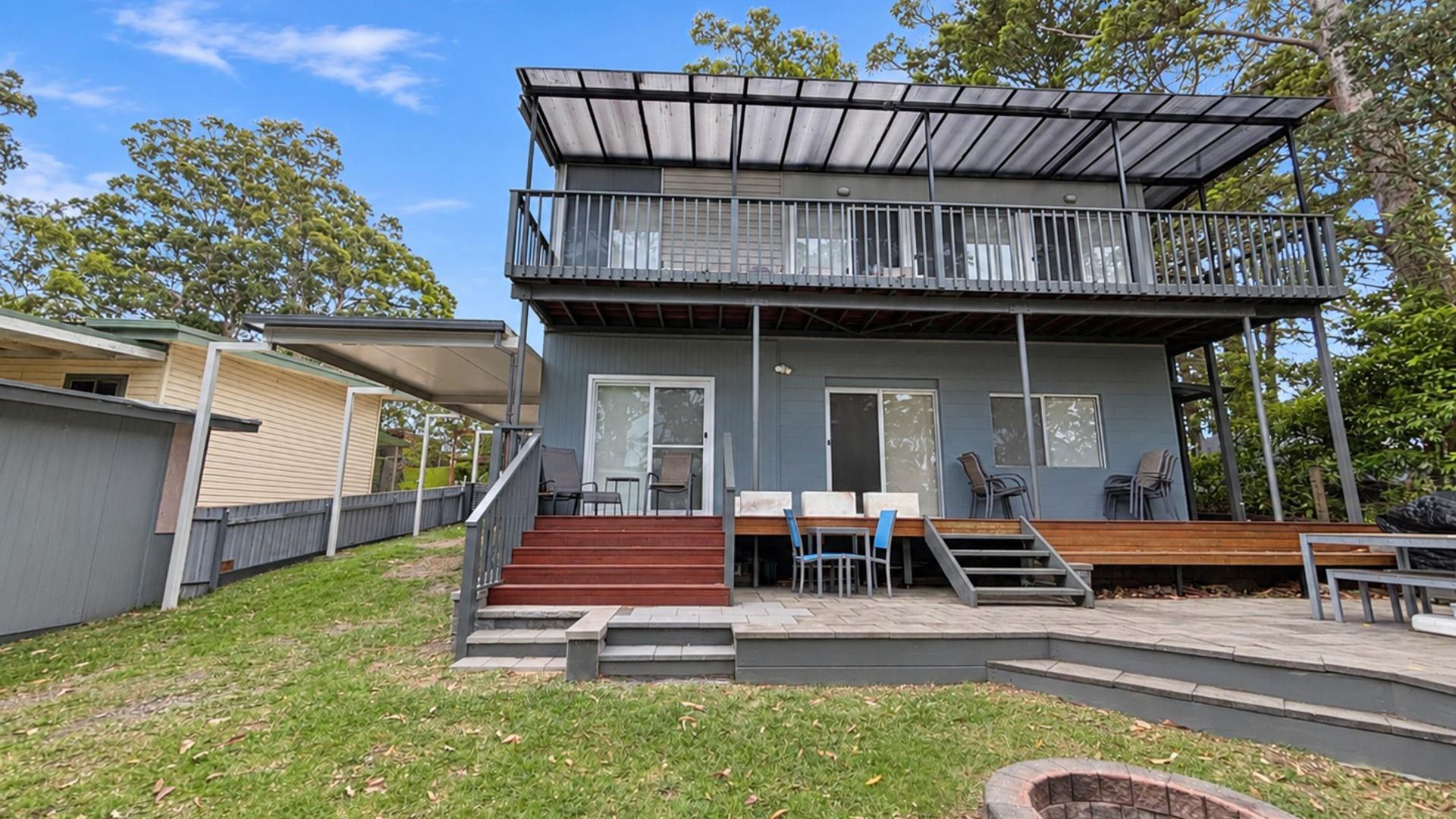 A two-story building with a balcony, outdoor seating, and a fire pit.