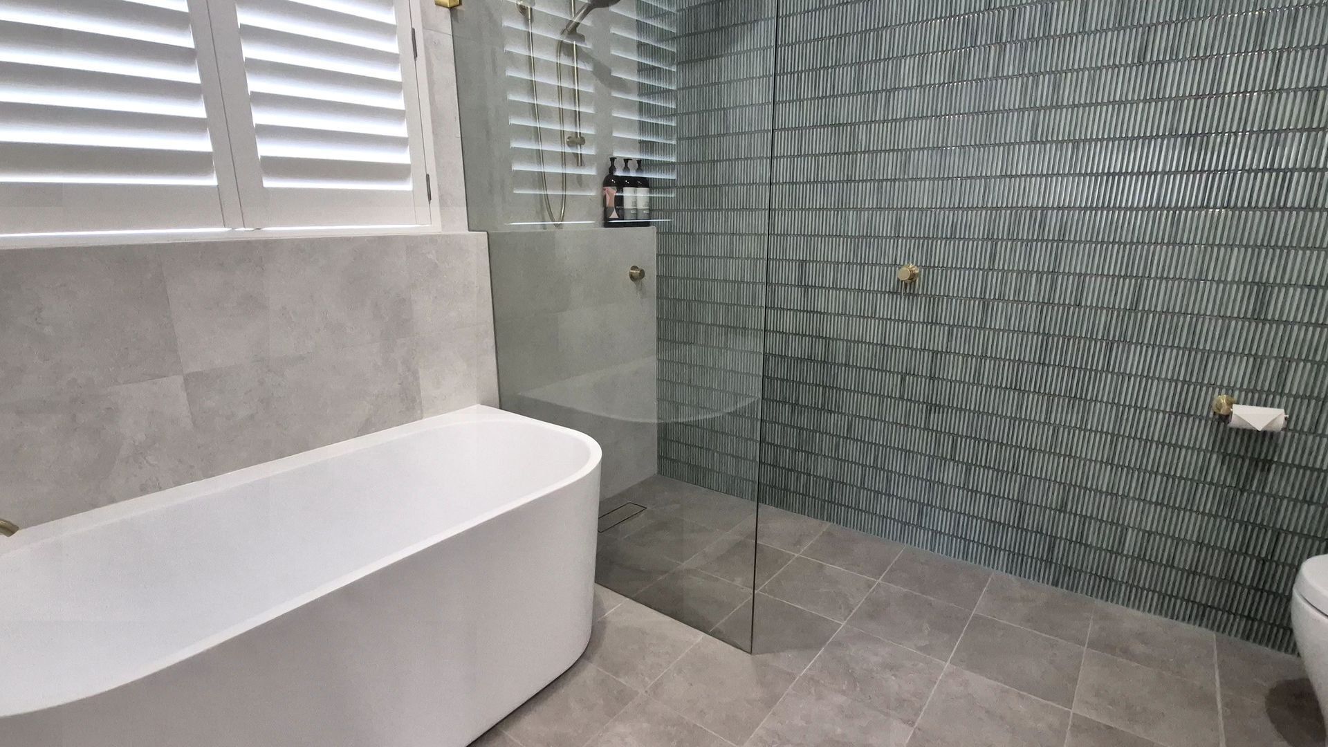 A modern bathroom with a freestanding bathtub, a glass-enclosed shower, and a tiled floor.