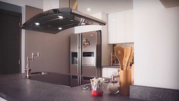 Una cocina moderna con una campana extractora de acero inoxidable, un horno empotrado y un refrigerador de dos puertas.