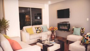 Una sala de estar moderna con un sofá, sillones, una mesa de centro y un televisor de pantalla plana montado en la pared.