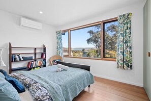 Une chambre à coucher avec un lit, une bibliothèque, une fenêtre avec des rideaux et une vue sur l’extérieur.