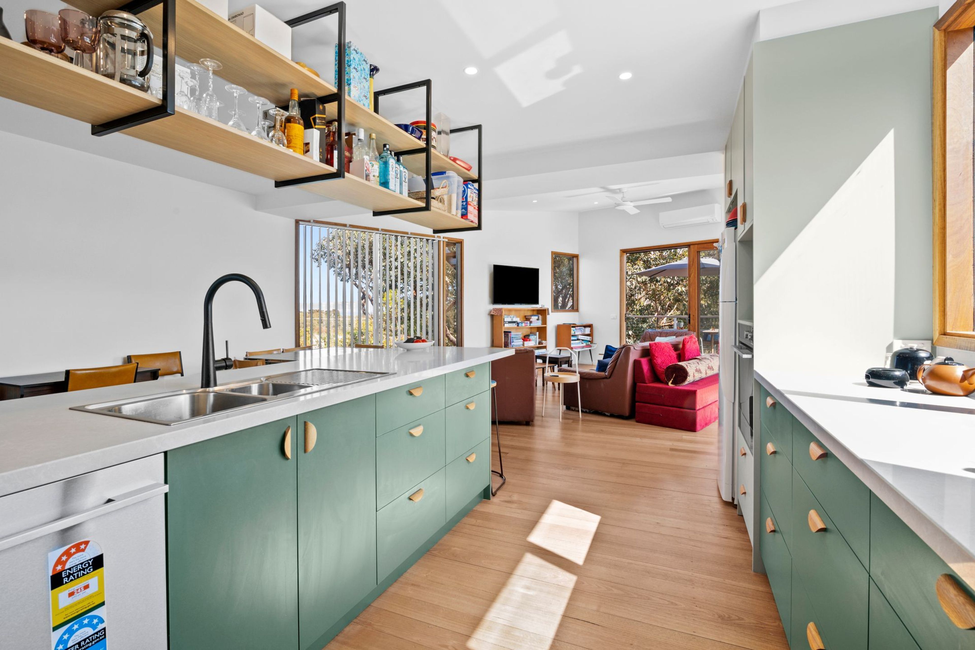 Una cocina moderna con una isla central, estanterías empotradas y un área de comedor con sofá y mesa.