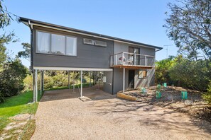 A two-story house with a covered patio, a balcony, and a garden area with plants. - Steppy Beach Retro (Aireys Inlet)