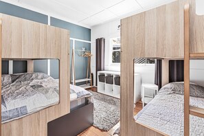 Une petite pièce avec des lits superposés, un petit bureau et une fenêtre avec des rideaux.