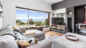 A modern living room with a large window, a fireplace, and a television. - Absolute Beachfront Views Apollo Bay (Apollo Bay)