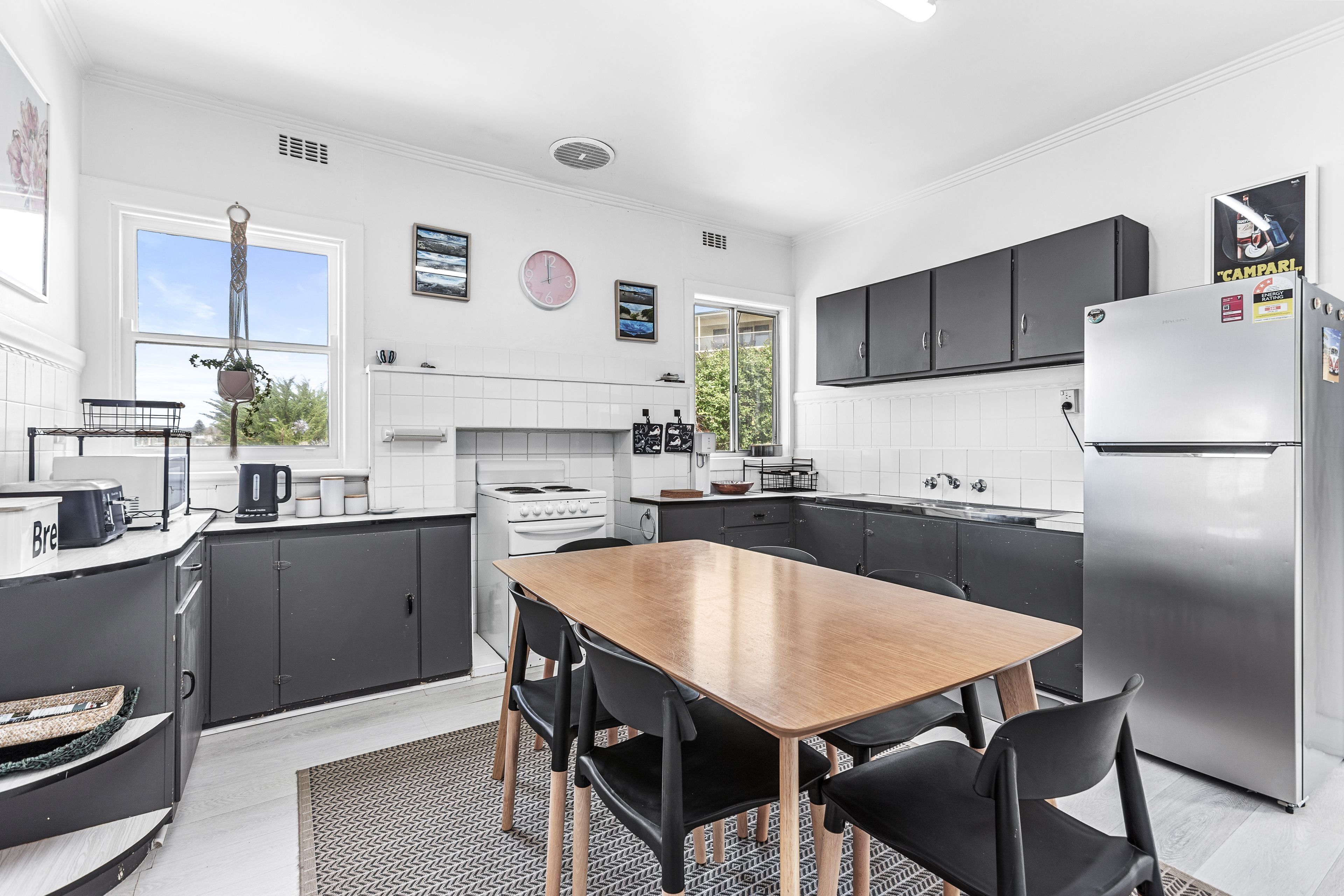 A modern kitchen with a central island, black cabinets, and a stainless steel refrigerator.