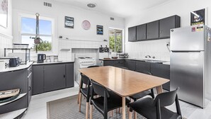 A modern kitchen with a central island, black cabinets, and a stainless steel refrigerator. - Absolute Beachfront Views Apollo Bay (Apollo Bay)