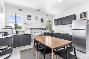 A modern kitchen with a central island, black cabinets, and a stainless steel refrigerator. - Absolute Beachfront Views Apollo Bay (Apollo Bay)