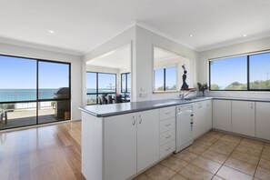 A modern kitchen with large windows, a view of the sea, and a balcony.