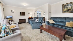 Een woonkamer met een bank, fauteuils, een salontafel en een televisietoestel.