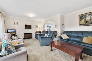 Ein Wohnzimmer mit einer Couch, Sesseln, einem Couchtisch und einem Fernseher.