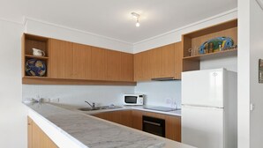 Eine moderne Küche mit Holzschränken, einer Marmorarbeitsplatte, einer Mikrowelle und einem Kühlschrank.