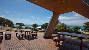 Una terrazza in legno con tavoli da picnic che si affaccia su una vista costiera.