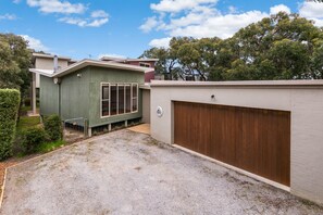 A residential property with a detached garage, a small shed, and a gravel driveway.