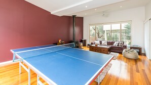 Une pièce avec une table de ping-pong, un canapé, une table basse et une grande fenêtre.