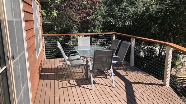 Enjoy a tranquil outdoor space with a glass-top table and four chairs, surrounded by lush greenery and trees.