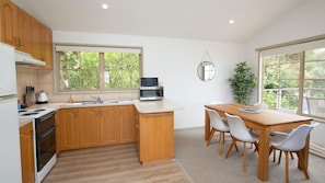 Enjoy meals in the kitchen with an oven and double sink, surrounded by a dining area with a wooden table and four chairs.