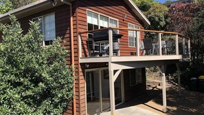 Enjoy a relaxing stay in this charming two-story house with a spacious balcony featuring a seating area and metal railing.