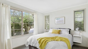 Relax in a serene bedroom with a large bed, bedside tables, and a framed picture.