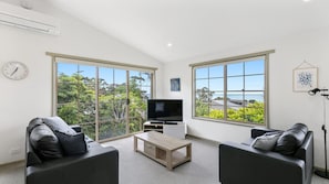 Relax in this serene space with a view, featuring a flat-screen TV, comfortable sofas, and a stylish coffee table.