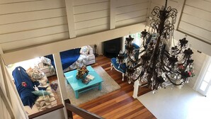 Ein geräumiges Wohnzimmer mit Treppe, einer Chandelieber und einem blauen Sofa.