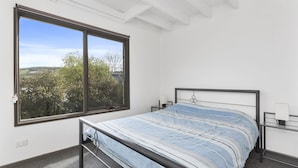 A bedroom with a bed, a window, and a view of trees. - Sea Loft (Apollo Bay)