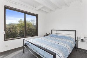 A bedroom with a bed, a window, and a view of trees. - Sea Loft (Apollo Bay)