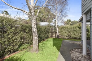 Une propriété résidentielle dotée d’une pelouse bien entretenue, d’un arbre et d’un mur en pierre.