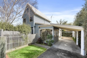 A residential property with a detached garage, a covered porch, and a well-maintained lawn.
