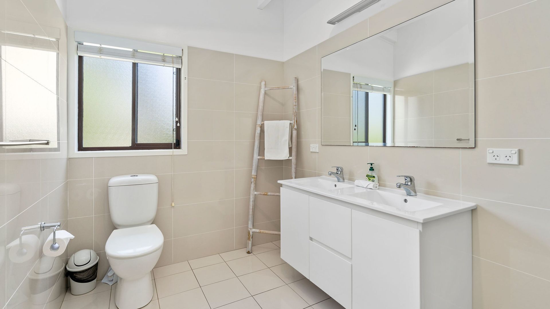 Un baño moderno con inodoro, bidé y tocador con espejo.