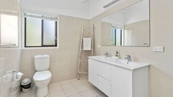 Un baño moderno con inodoro, bidé y tocador con espejo.