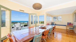 Enjoy meals with a view of the ocean from this dining area featuring a large table and comfortable chairs.